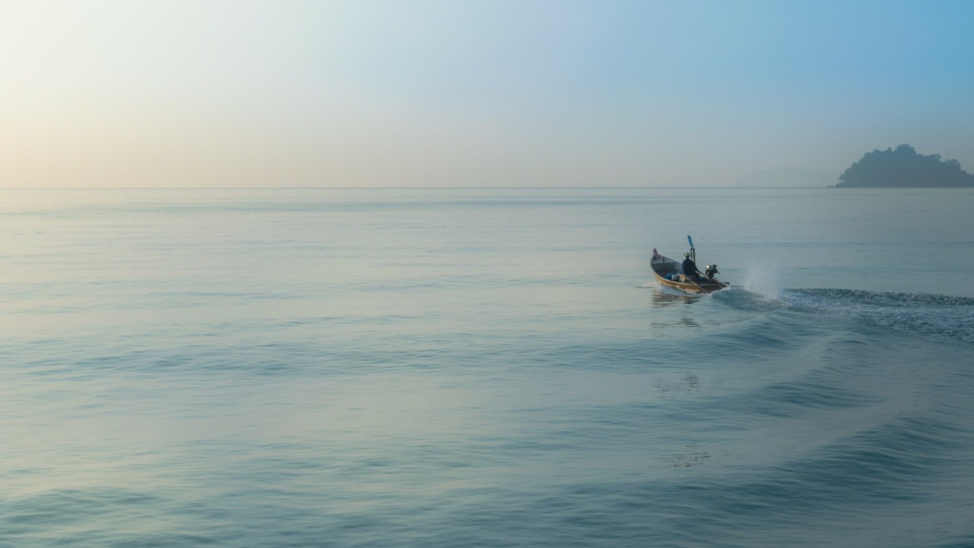 Small wooden fishing boat heading out to sea